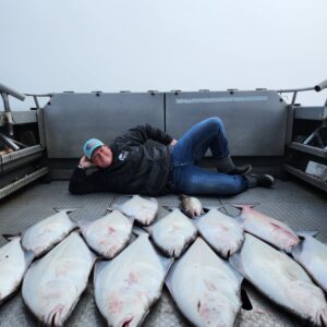 Fishing group standing behind their full catch of halibut, cod, and rockfish.